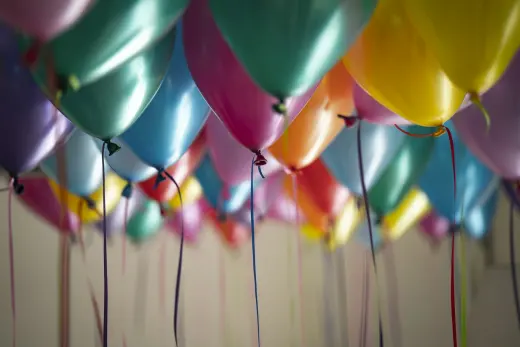 Coloured balloons with ribbons floating against a ceiling
