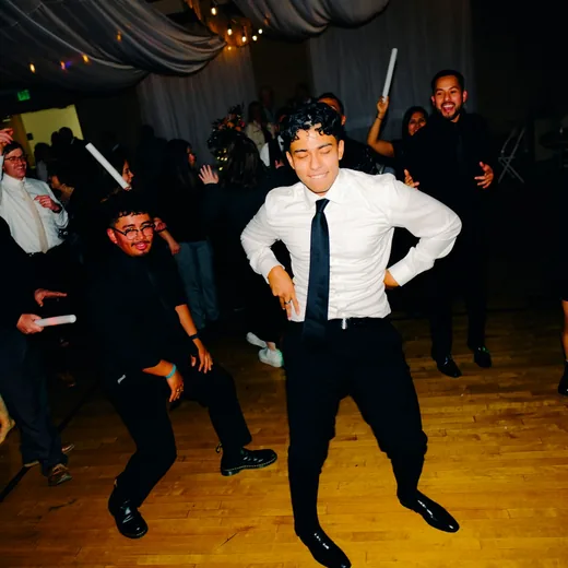 A boy dancing on the floor with glow sticks as other guests join in