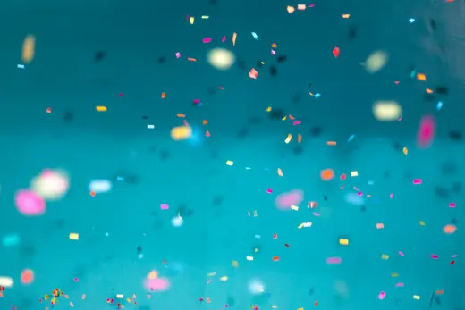 Coloured confetti falling against a teal backdrop