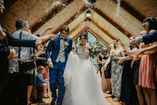 A newly married couple walking out through a confetti toss