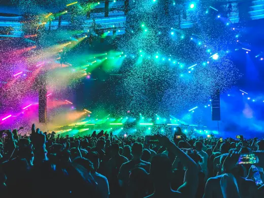 A crowd under coloured stage lights and falling confetti