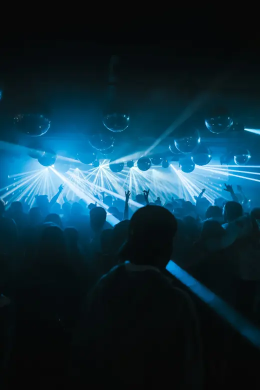 A dance floor crowd under disco balls and blue lights