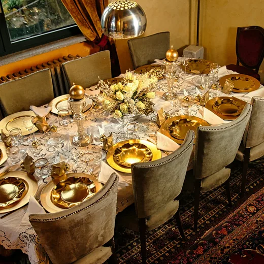 A private dining room set with gold plates and candles before guests arrive