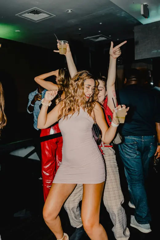 Friends dancing with drinks at a party