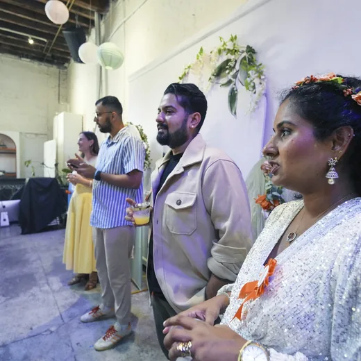 Guests standing and talking in a room decorated with paper lanterns and greenery