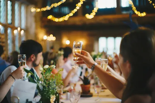 Guests raising glasses for a toast under string lights