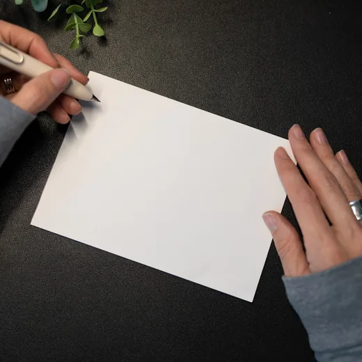 Hands writing a message on a blank card