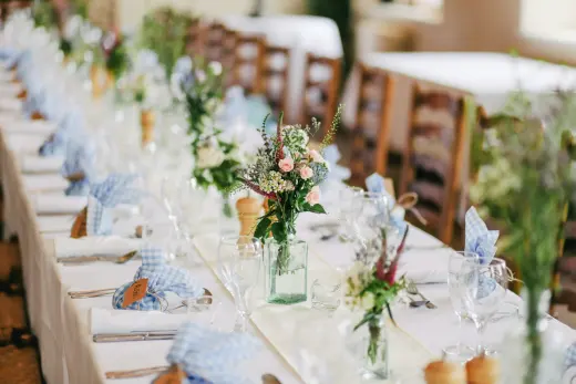 A long table set with wildflowers and gingham napkins