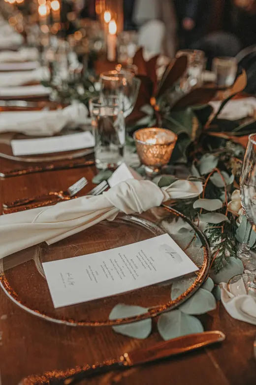 A place setting with a menu card and a greenery runner
