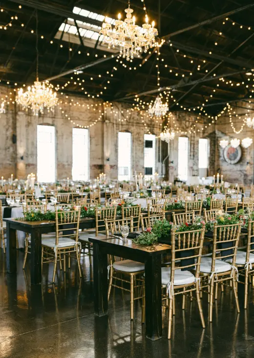A reception hall set with gold chairs under chandeliers