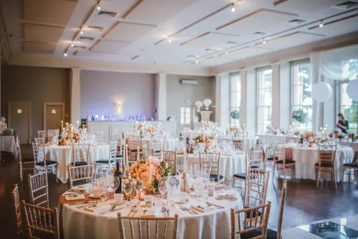 Round tables set with peach florals in a reception room
