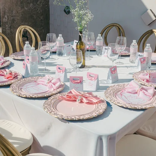 A table set with pink plates, place cards and glasses before guests arrive