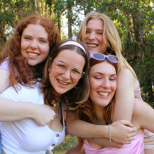 Four teenage friends hugging and laughing together