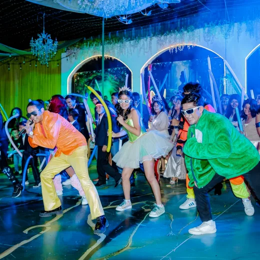 Teenagers dancing with glow sticks under coloured light