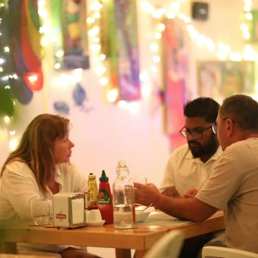 Three friends talking across a table over a meal