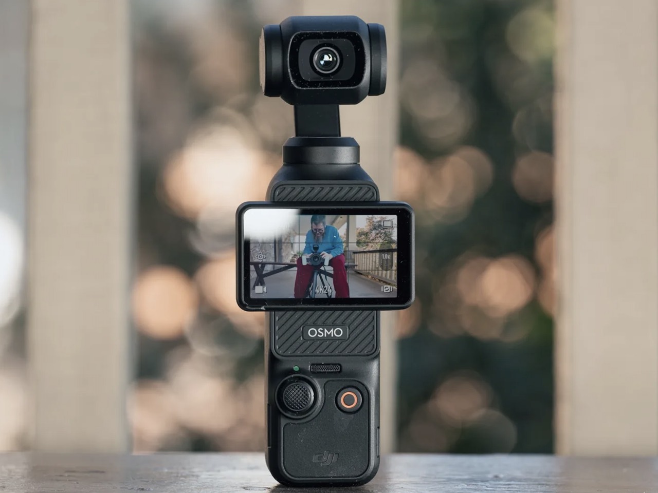 A pocket 4K camera standing on a table, screen showing its live view
